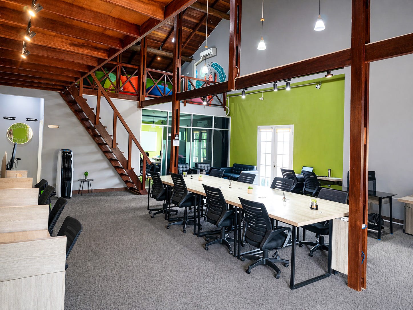 Shared workspace with desks, ergonomic chairs, and natural light from the windows